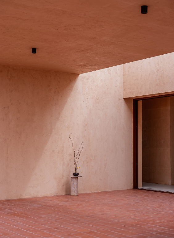 Earth-toned courtyard corner with terracotta-tile floor and a single potted plant