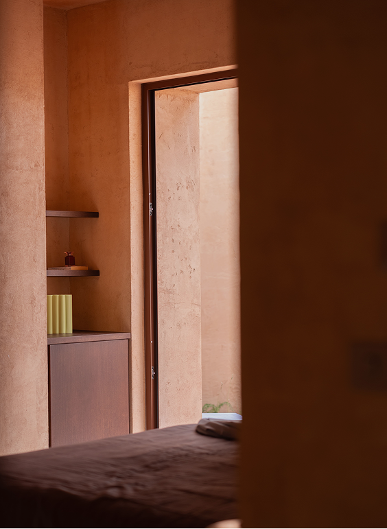 Glimpse from the bed through a doorway into an adjoining room with built-in shelving