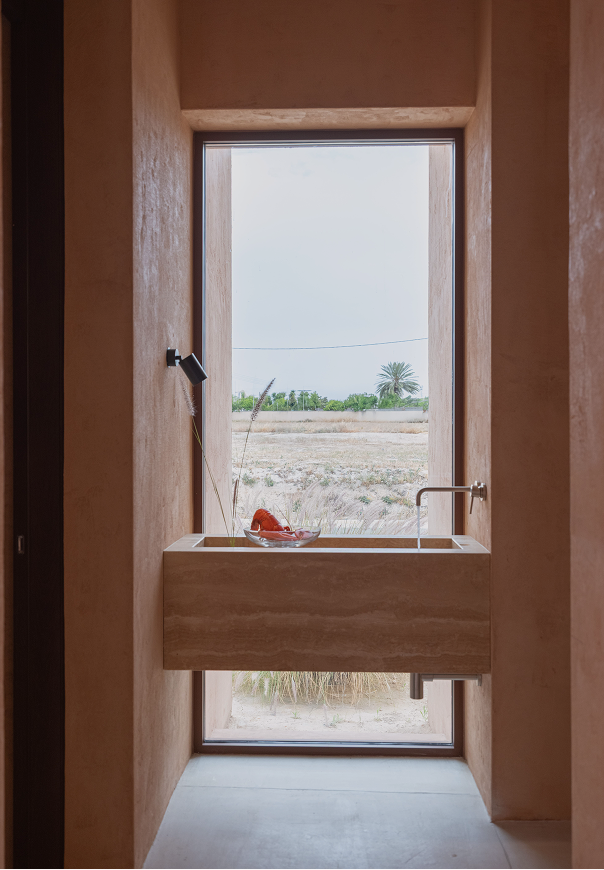 Tall narrow window framing the horizon above a wooden window seat