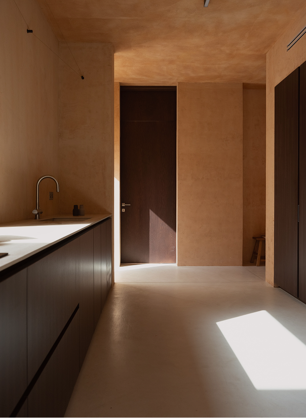 Galley kitchen with dark cabinetry and a sink, sunlight falling across the floor