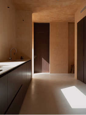 Kitchen interior with a sink counter at left and a dark door at the corridor's end