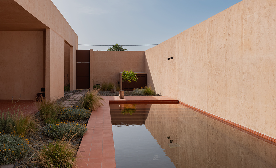Inner courtyard with a reflecting pool flanked by terracotta walls and ornamental grasses