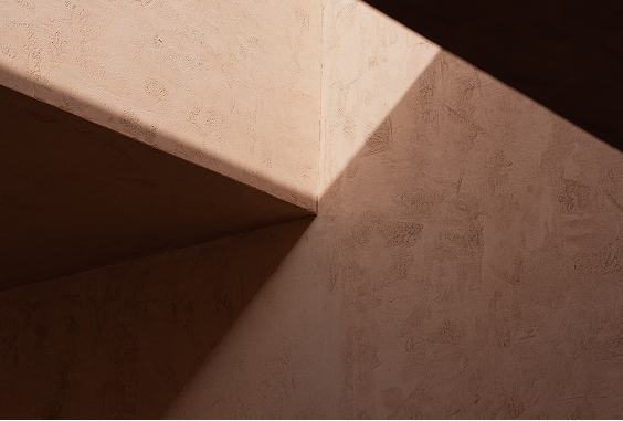 Close-up of a beam meeting the terracotta wall with light grazing the textured surface