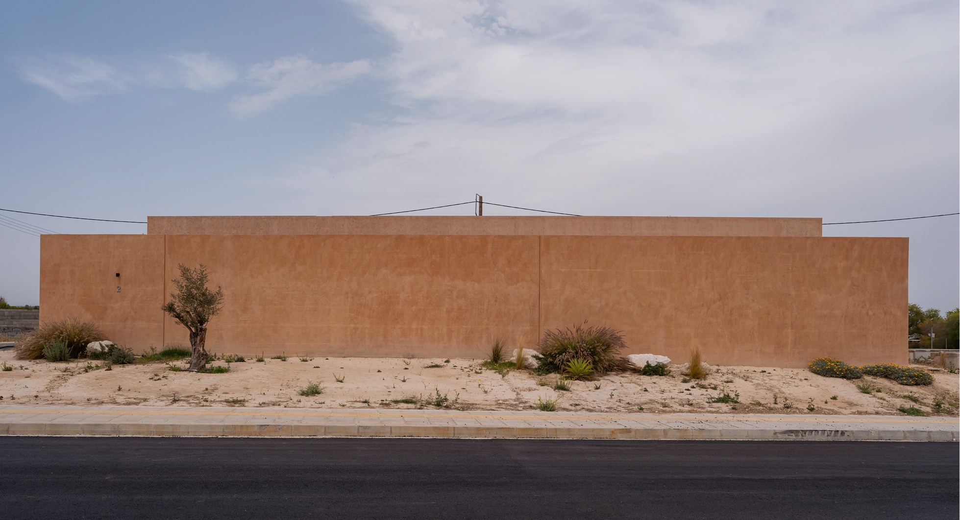 Homa House terracotta facade running along the road under a desert sky